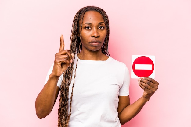 Junge afroamerikanische Frau mit einem verbotenen Schild isoliert auf rosa Hintergrund