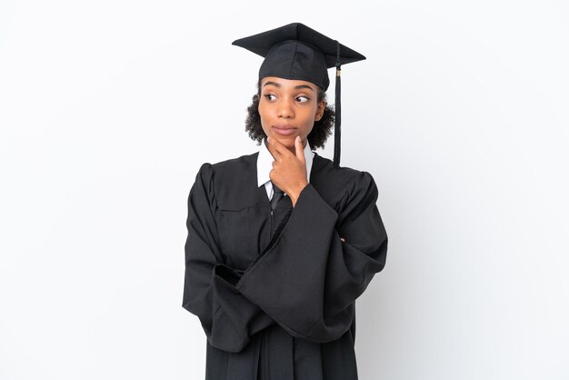 Junge afroamerikanische Frau mit Hochschulabschluss isoliert auf weißem Hintergrund, die zur Seite schaut