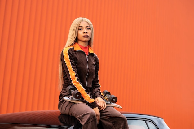 Junge afroamerikanische Frau mit langen blonden Haaren und Sportbekleidung auf orangefarbenem Hintergrund