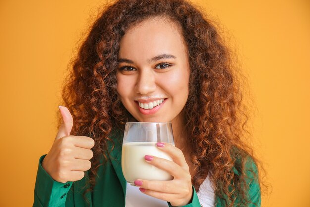 Junge afroamerikanische Frau mit Milch, die Daumen oben zeigt