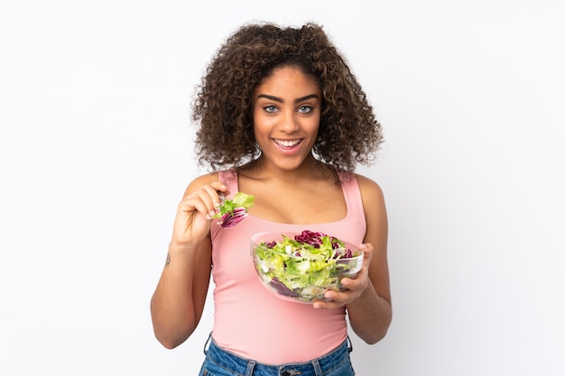 Junge afroamerikanische Frau mit Salat auf weißer Wand