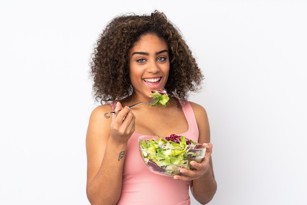 Junge afroamerikanische Frau mit Salat auf weißer Wand