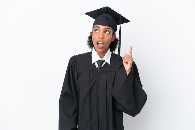 Junge afroamerikanische Frau mit Universitätsabschluss, isoliert auf weißem Hintergrund, denkt eine Idee, die mit dem Finger nach oben zeigt