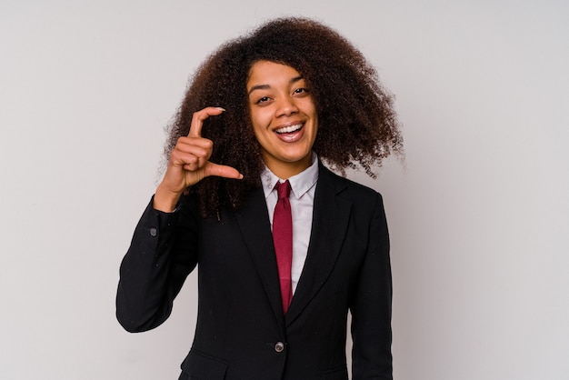 Junge afroamerikanische Geschäftsfrau, die einen Anzug lokalisiert auf weißem Hintergrund hält, der etwas wenig mit Zeigefingern, lächelnd und zuversichtlich hält.