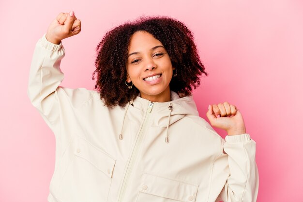 Junge afroamerikanische Mischrassenfrau isoliert, die einen besonderen Tag feiert, springt und Arme mit Energie hebt.