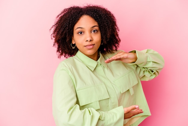 Junge afroamerikanische Mischrassenfrau isoliert, die etwas mit beiden Händen, Produktpräsentation hält.