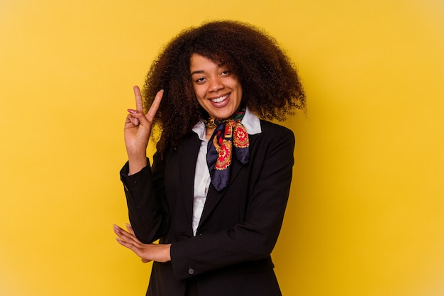 Junge afroamerikanische Stewardess lokalisiert auf gelb, die Nummer zwei mit den Fingern zeigend.