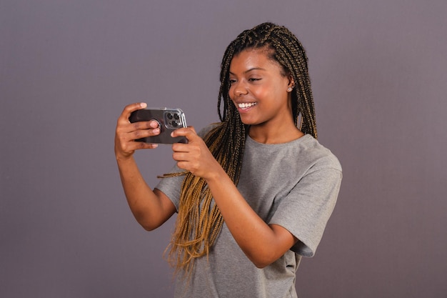 Junge afrobrasilianische Frau, die etwas per Handy-Smartphone anschaut