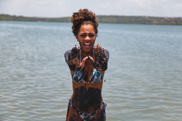 Junge Afrofrau, die im natürlichen Lehm im Fluss badet.