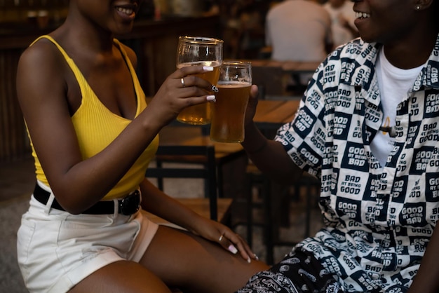 Junge Afropaare in einem Nachtclub, die mit Bier anstoßen. Kurze Einstellung, keine Gesichter.