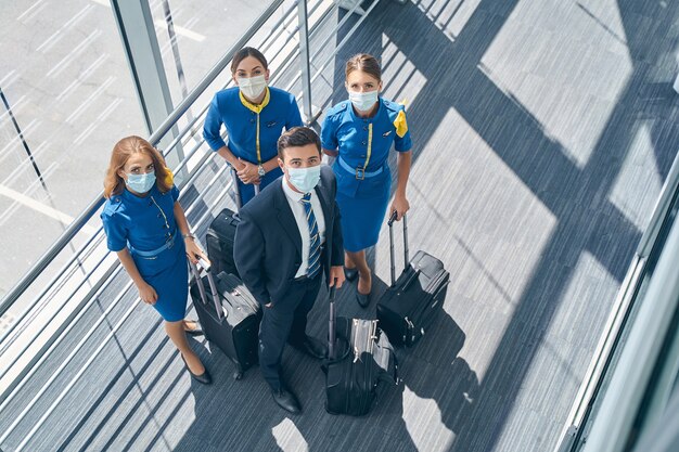 Foto junge airline-mitarbeiter stehen mit ihren trolleys am flughafenterminal