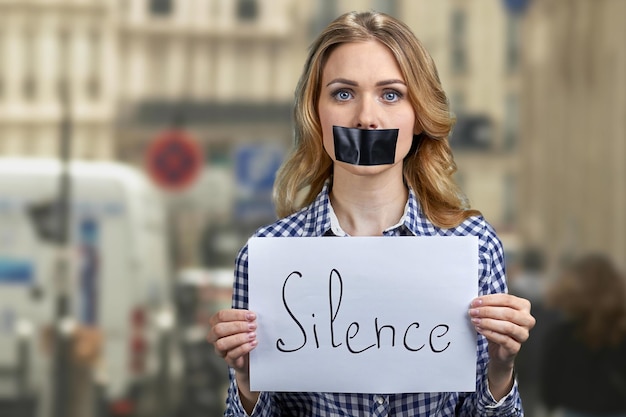 Junge Aktivistin hält Banner mit handgeschriebener Aufschrift Silence.