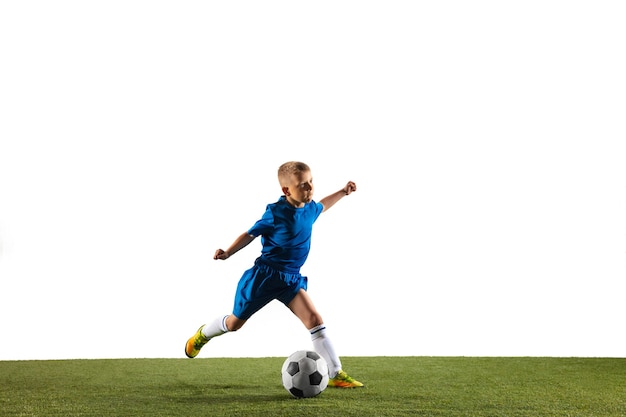 Junge als Fußball- oder Fußballspieler in Sportbekleidung, der eine Finte oder einen Tritt mit dem Ball für ein Tor an der weißen Wand macht.