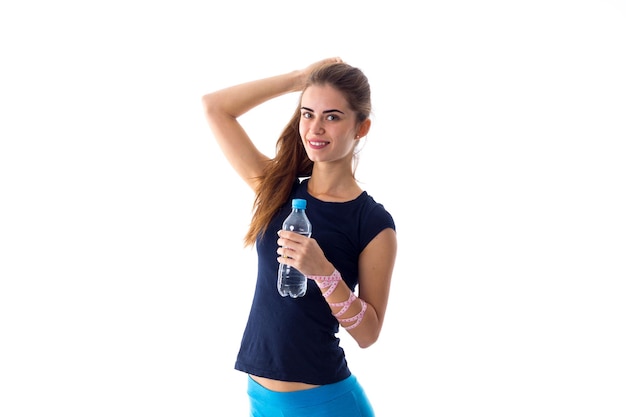 Junge angenehme Frau im blauen T-Shirt mit Zentimeter um ihre Taille, die eine Flasche Wasser öffnet