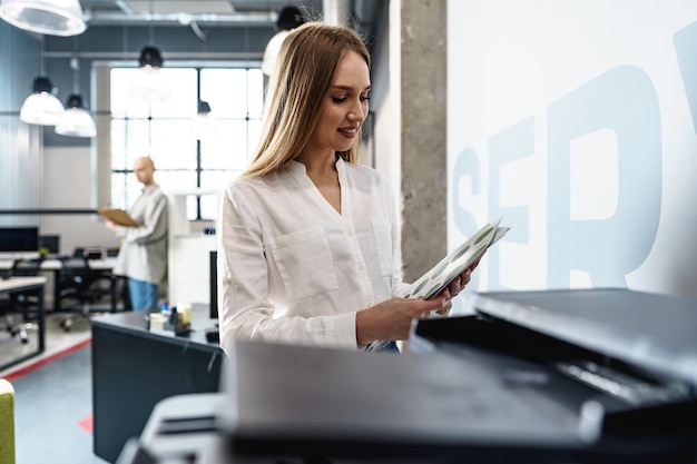 Junge Angestellte mit modernem Drucker im Büro