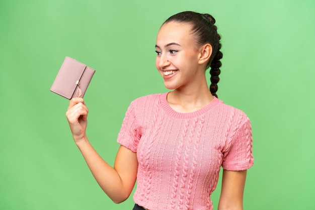 Junge arabische Frau, die eine Brieftasche über isoliertem Hintergrund mit glücklichem Gesichtsausdruck hält