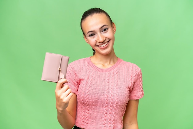 Junge arabische Frau, die eine Brieftasche über isoliertem Hintergrund mit glücklichem Gesichtsausdruck hält