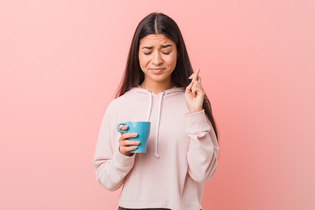 Junge arabische Frau, die Finger einer Schalenüberfahrt für das Haben des Glücks hält