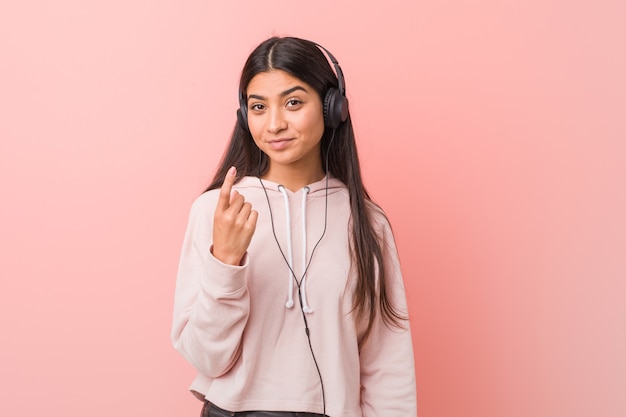 Junge arabische Frau, die Musik hört, die mit dem Finger auf Sie zeigt, als ob die Einladung näher kommt.