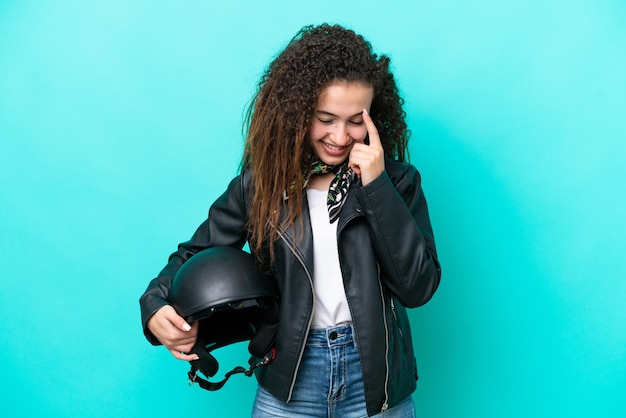 Junge arabische Frau mit einem Motorradhelm isoliert auf blauem Hintergrund lachend