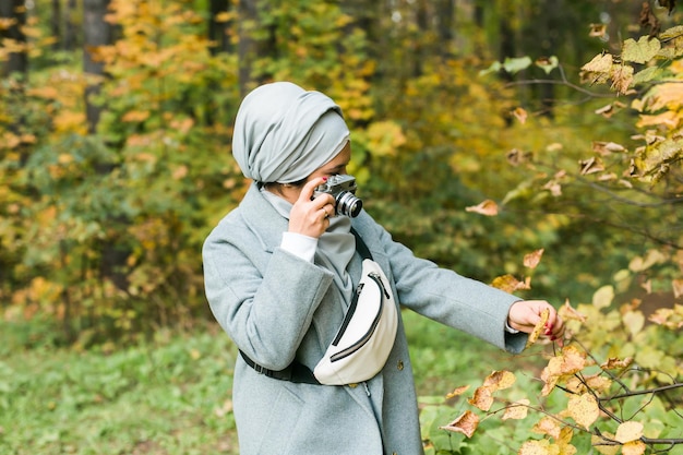 Junge arabische frau mit hijab-kopftuch fotografieren mit einem smartphone im park modernes muslimisches mädchen