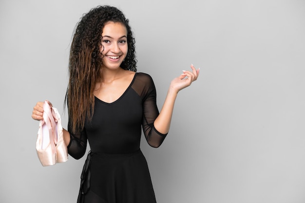 Junge arabische frau tanzt ballett isoliert auf grauem hintergrund und streckt die hände zur seite, um zum kommen einzuladen