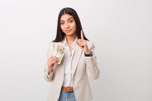 Junge arabische Geschäftsfrau, welche die Dollar zeigen Nummer Eins mit dem Finger hält.