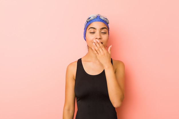 Junge arabische Schwimmerfrau isolierte Gähnen, das eine müde Geste zeigt, die Mund mit Hand bedeckt.