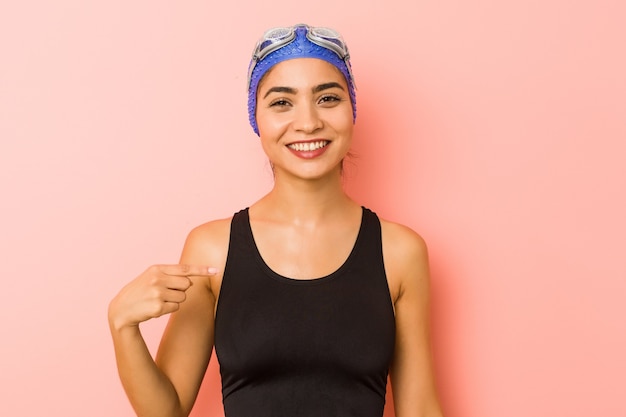 Junge arabische Schwimmerfrau isolierte Person, die von Hand auf einen Hemdkopierraum zeigt, stolz und zuversichtlich