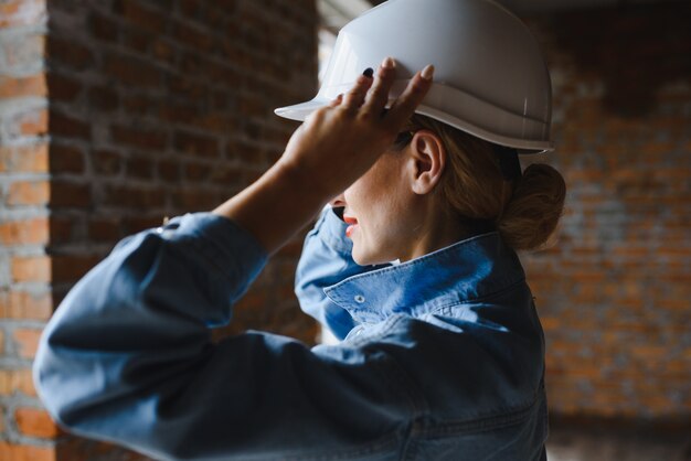 Junge Arbeiterin mit weißem Helm auf der Baustelle.