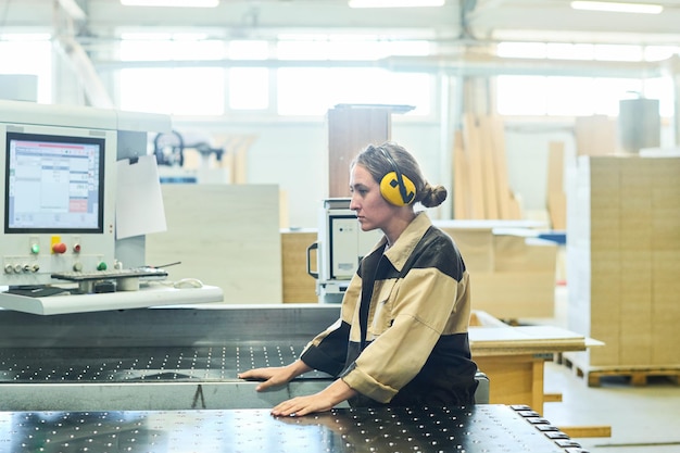 Junge Arbeitnehmerin, die an der Maschine arbeitet