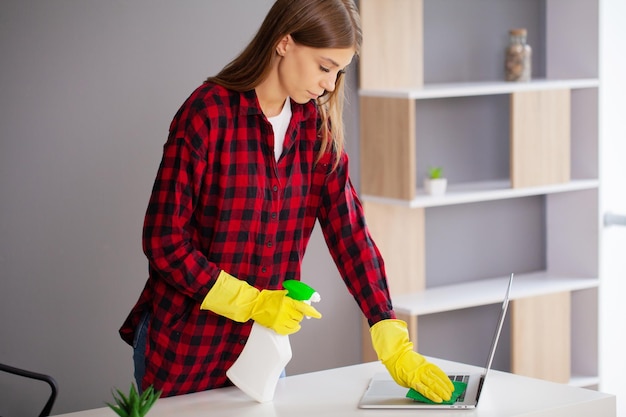 Junge Arbeitskraft-Reinigungs-Schreibtisch mit Lappen im Büro