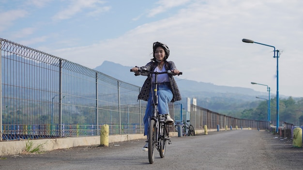 Junge Asiatin fährt mit dem Fahrrad zur Arbeit, sie ist glücklich und sicher