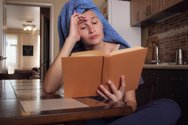 Junge Asiatin liest ein Buch in der Küche