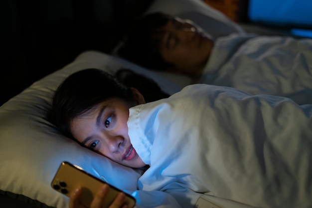 Junge Asiatin mit Smartphone um Mitternacht