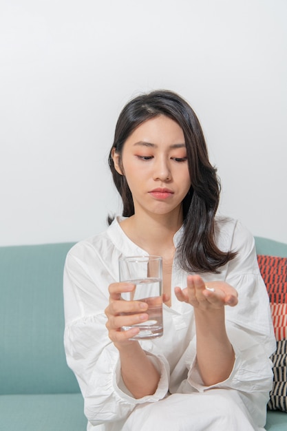 Junge Asiatin nimmt Medizin im Wohnzimmer ein