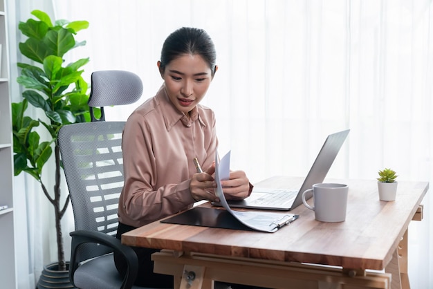 Junge asiatische begeisterte Geschäftsfrau am modernen Schreibtisch mit Laptop