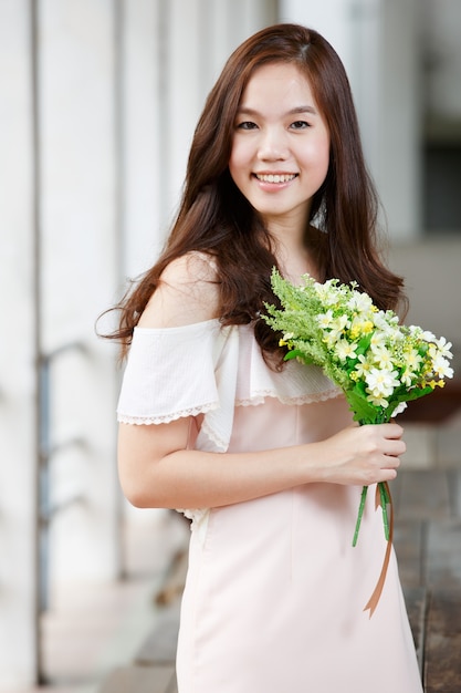 Junge asiatische Dame, die Blumen in ihren Händen hält