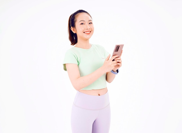 Junge asiatische Dame zeigt leeren Smartphone-Bildschirm mit positivem Ausdruck lächelt breit in Freizeitkleidung gekleidet und fühlt sich auf blauem Hintergrund glücklich. Mobiltelefon mit weißem Bildschirm in weiblicher Hand