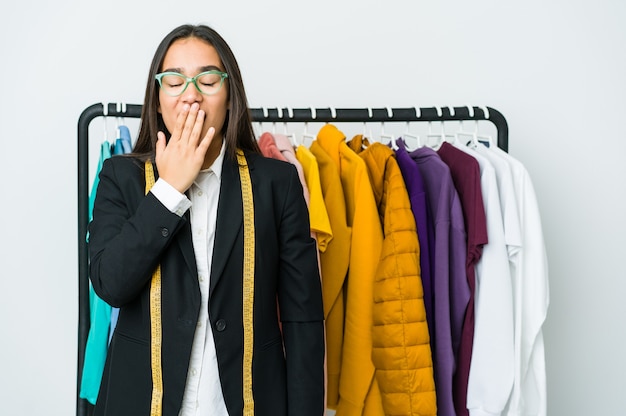 Junge asiatische Designerfrau lokalisiert auf weißem Wandgähnen, das eine müde Geste zeigt, die Mund mit Hand bedeckt.