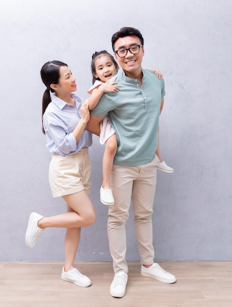 Junge asiatische Familie, die auf Hintergrund steht