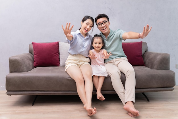 Junge asiatische Familie, die auf Sofa sitzt