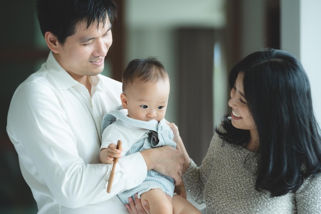 Junge asiatische Familie ist glücklich zusammen zu Hause durch das Lebensversicherungskonzept Kind Baby und Mutter und Vater haben Spaß und lächeln mit Liebe Kindheit leben in gemütlichem Lebensstil mit Vater und Mutter