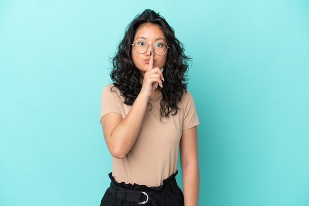 Junge asiatische Frau auf blauem Hintergrund isoliert, die ein Zeichen der Stille zeigt, Geste, die den Finger in den Mund steckt