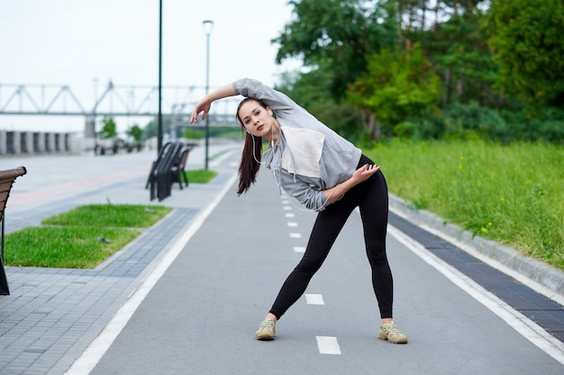 Junge asiatische Frau der Eignung, die Beine nach Lauf ausdehnt. draußen nach dem Lauf