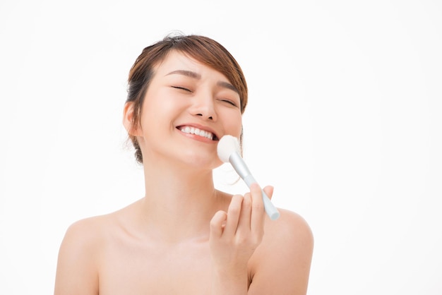 Foto junge asiatische frau des schönheitsporträts lächelt mit bürstenbackenhautpflege- und -kosmetikkonzept