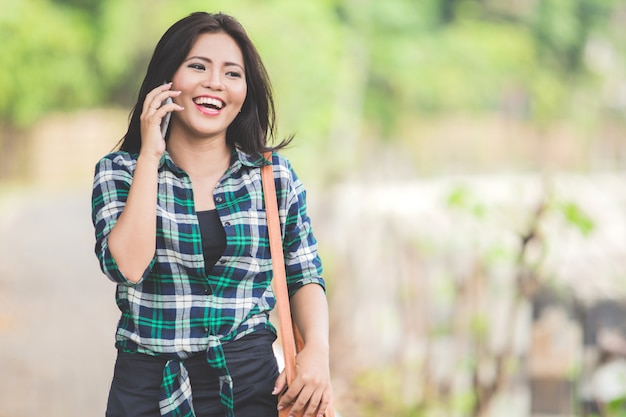 Junge asiatische Frau, die am Telefon spricht, während sie auf dem Par geht