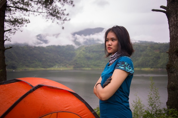 Junge asiatische Frau, die Camping oder Picknick im Waldsee kampiert.