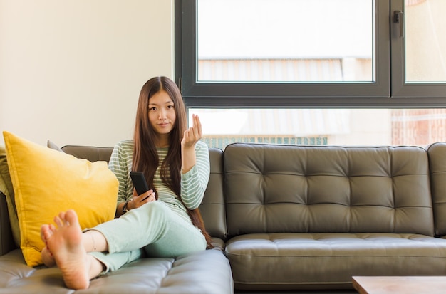 Junge asiatische Frau, die Capice oder Geldgeste macht und Ihnen sagt, dass Sie Ihre Schulden bezahlen sollen!