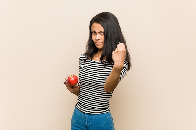 Junge asiatische Frau, die einen Apfel zeigt Faust hält